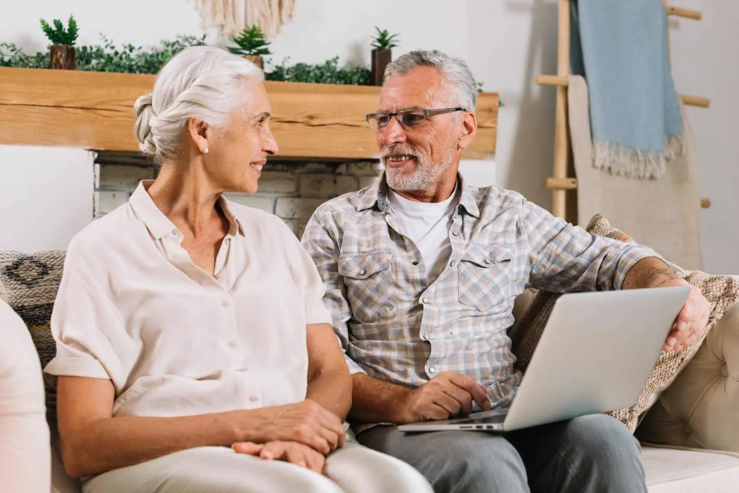 An older couple on a sofa talking through their Medicare insurance choices on a laptop